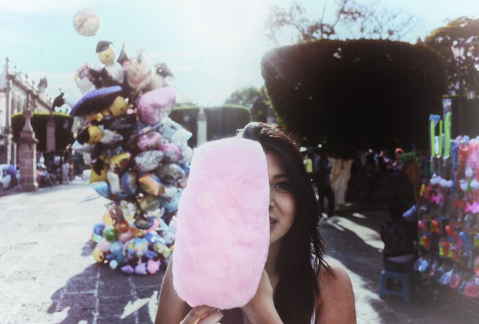 woman-holding-cotton-candy-with-balloons-in-background-763021