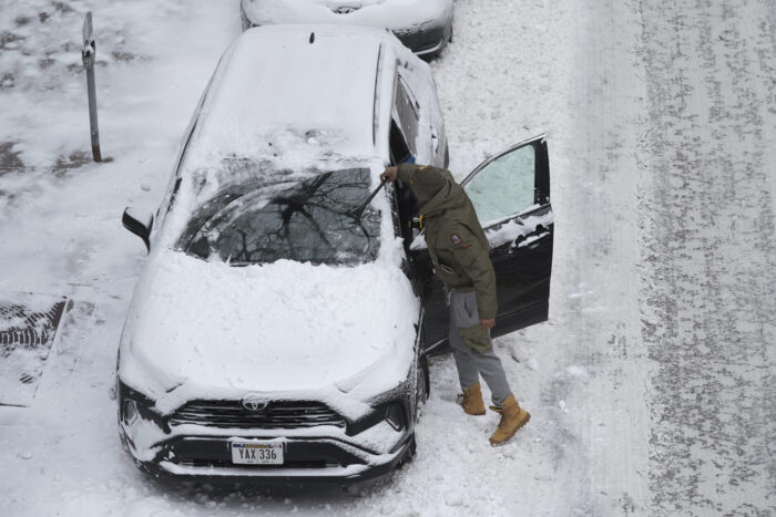 A man clears snow off his car parked on a downtown street, Thursday, Dec. 22, 2022, in Des Moines, Iowa. Temperatures plunged far and fast Thursday as a winter storm formed ahead of Christmas weekend, promising heavy snow, ice, flooding and powerful winds across a broad swath of the country and complicating holiday travel. (AP Photo/Charlie Neibergall)